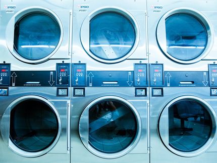 A row of washing machines are stacked on top of each other in a laundromat