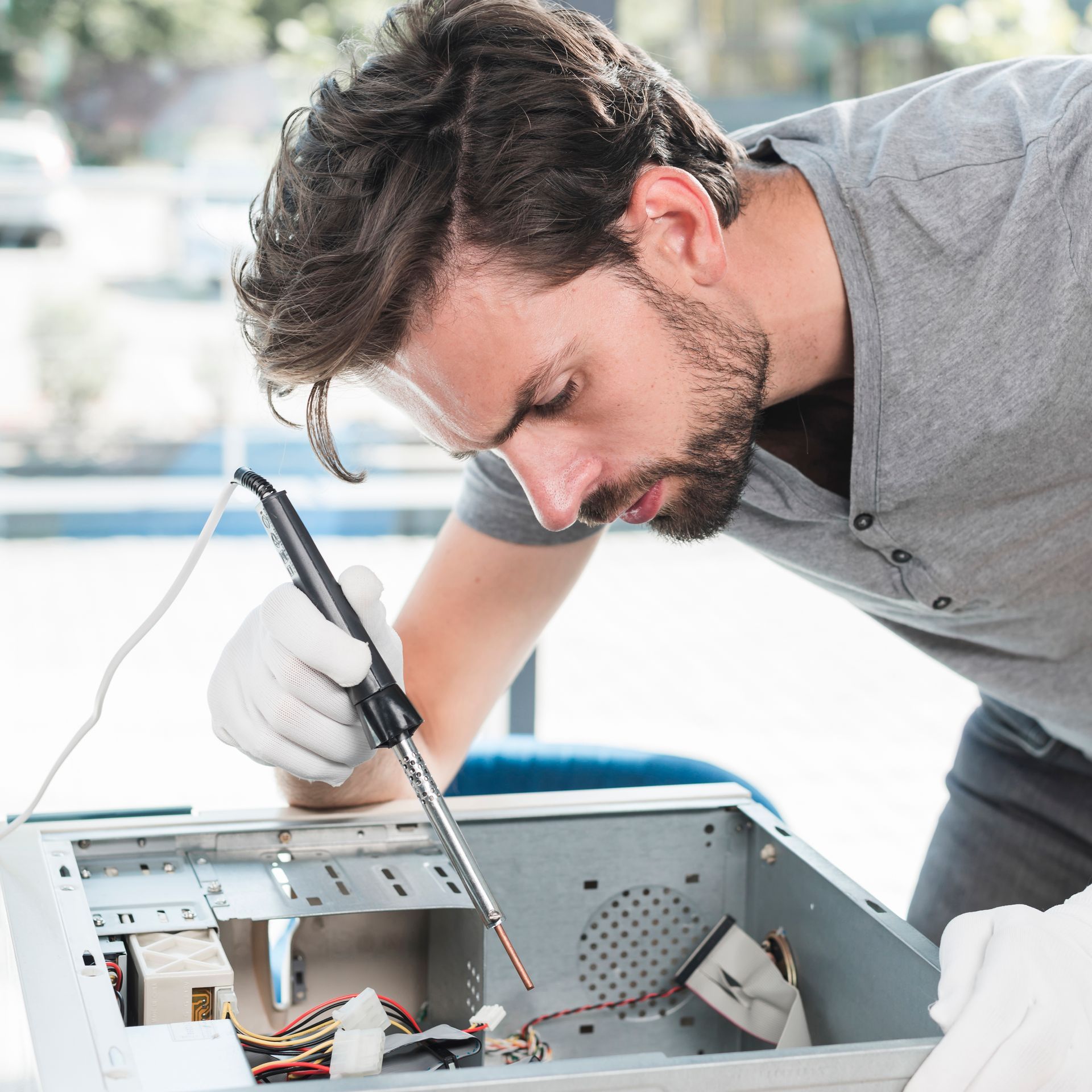 A man is working on a computer with a soldering iron