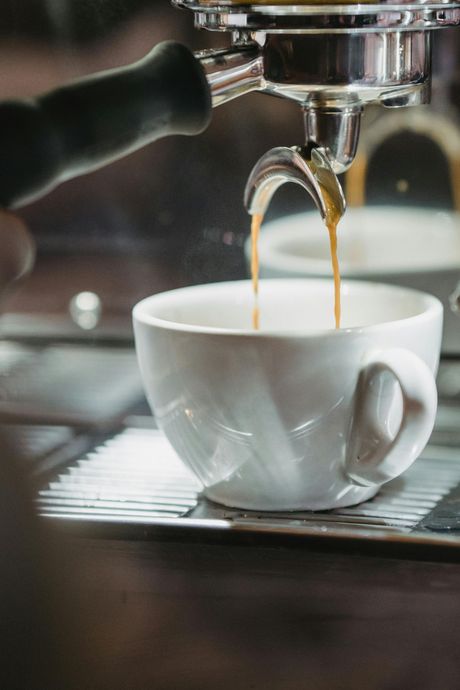 Espresso machine pouring coffee into a white ceramic cup.