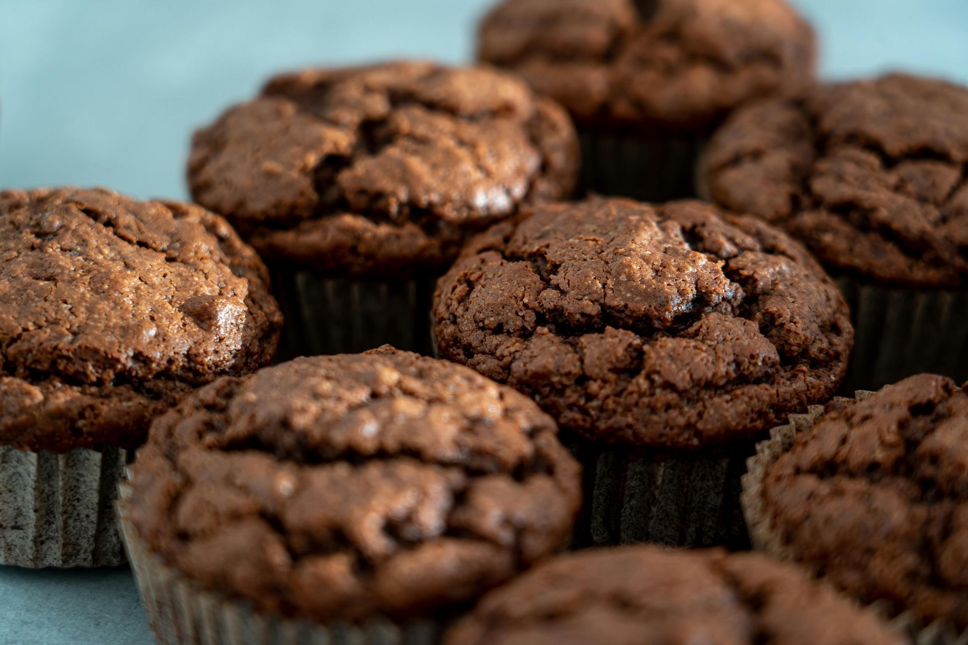Chocolate muffins in paper liners, arranged in a close-up view.