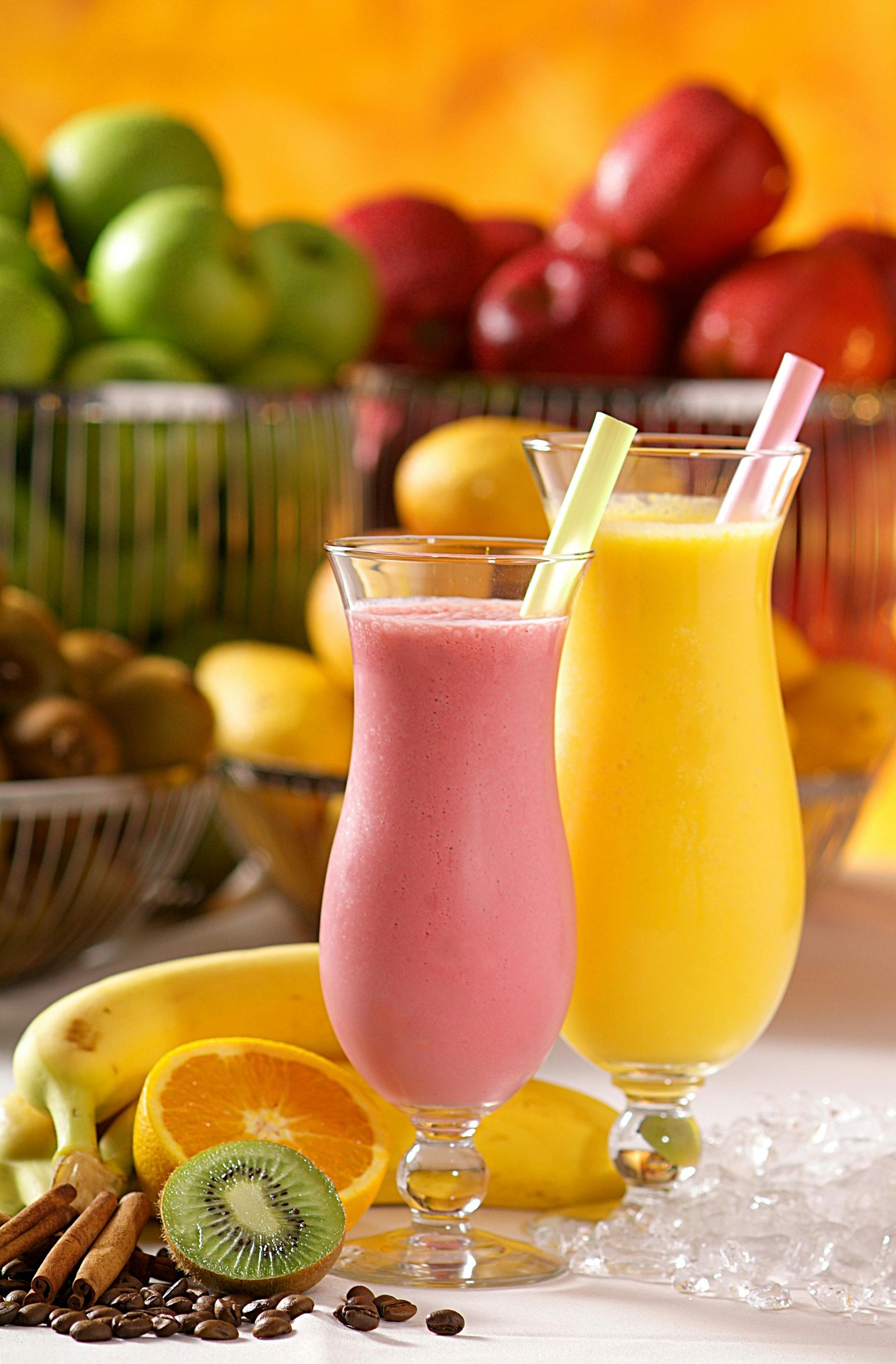 Two smoothies: one pink, one yellow, with fruit and ice.