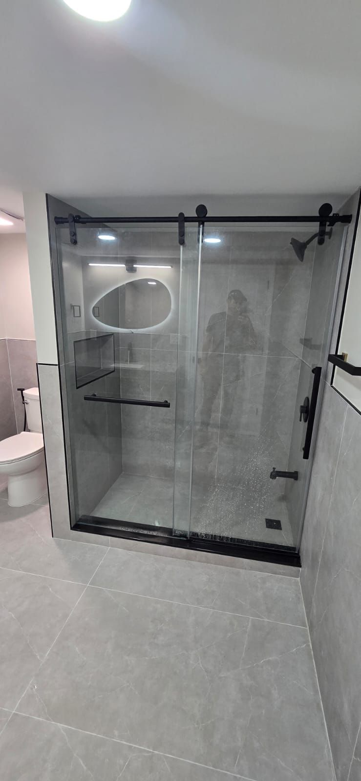 A modern bathroom with a black-framed sliding glass shower door