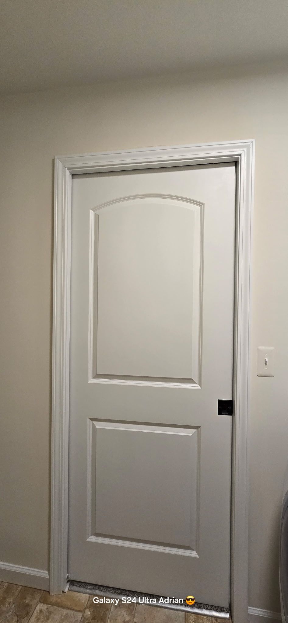 A white door with an arched top panel and a rectangular bottom panel