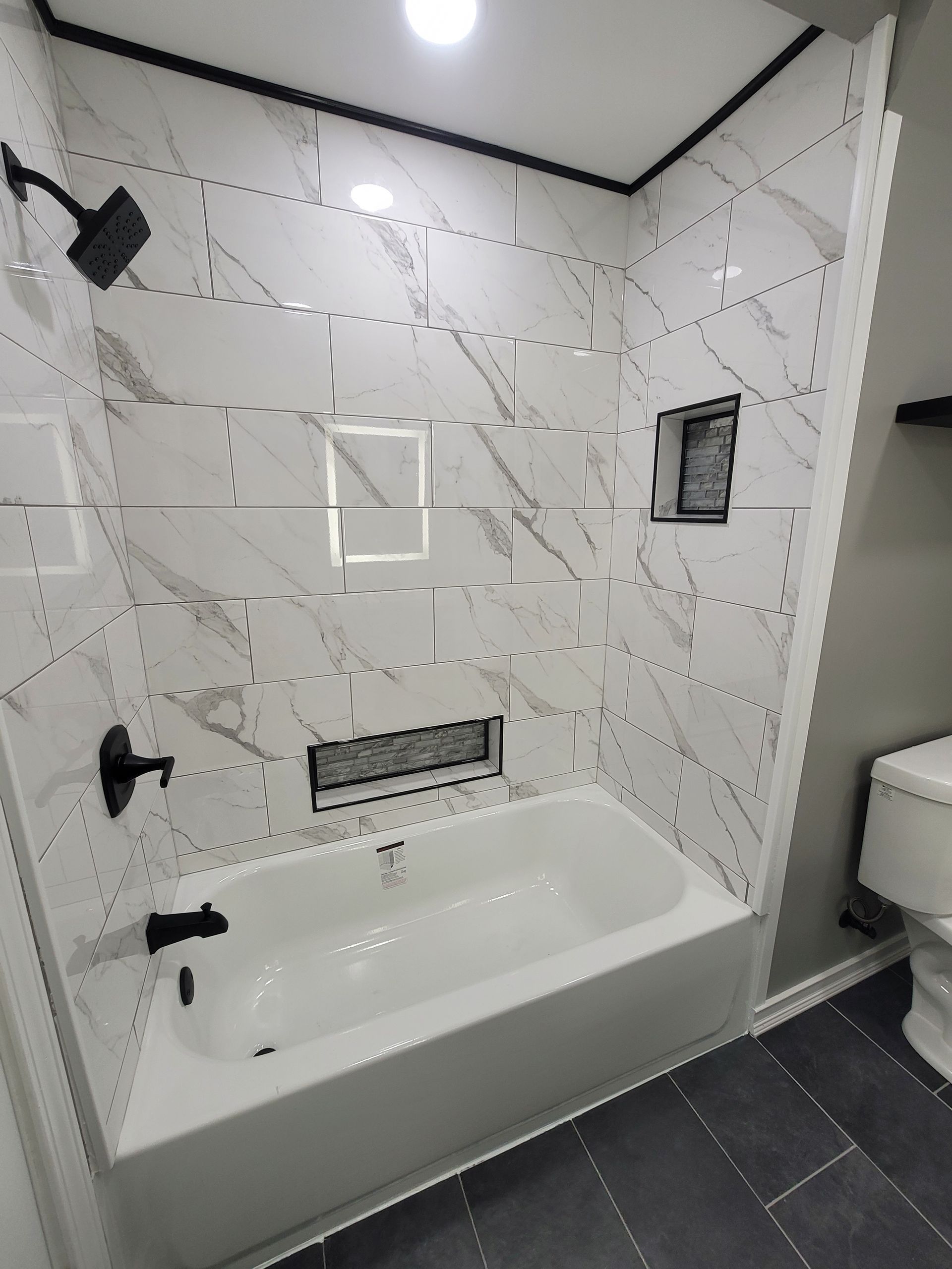 A newly renovated bathroom with white marble-look tiles
