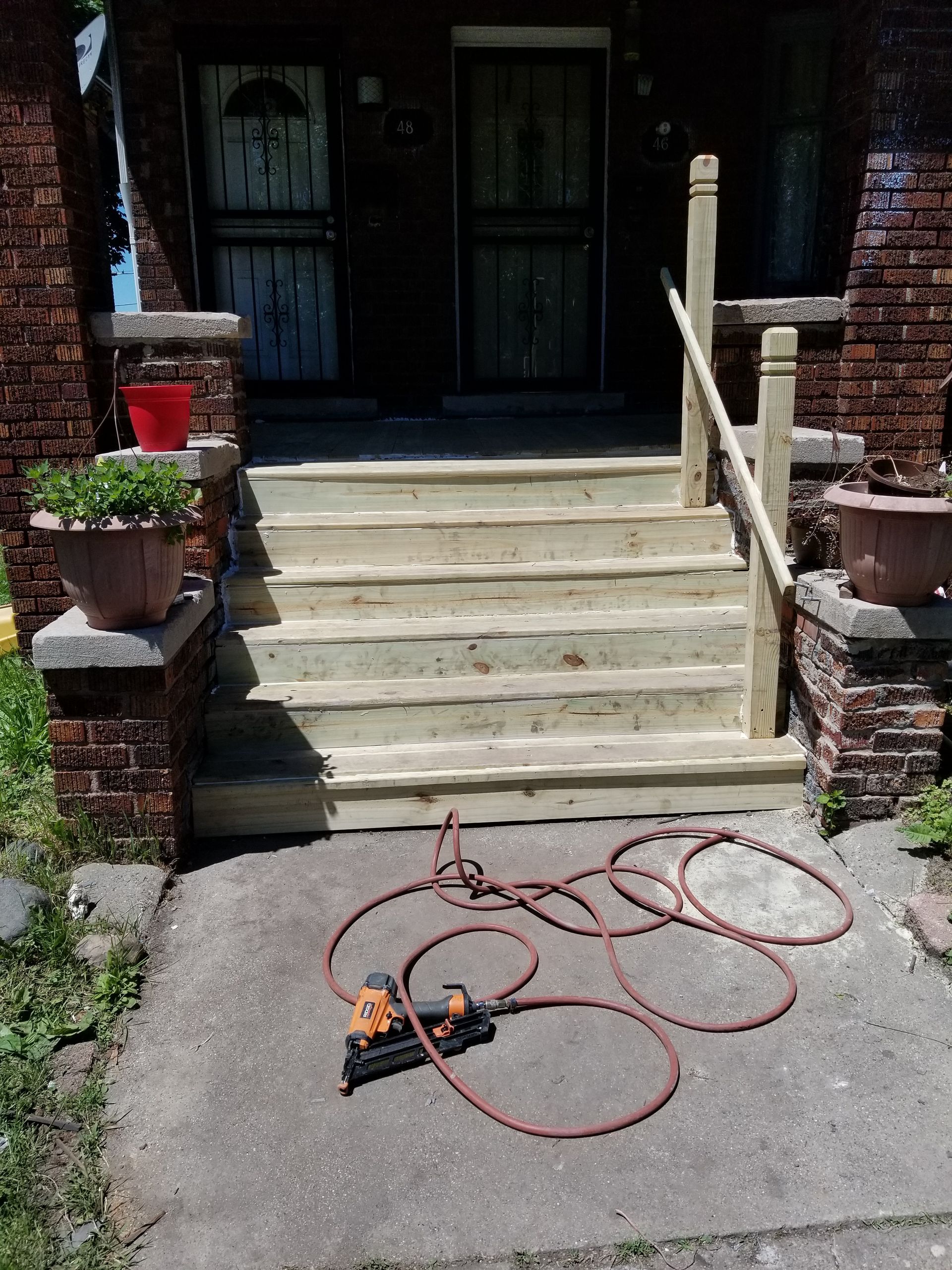 Newly built wooden steps leading up to a brick house entrance