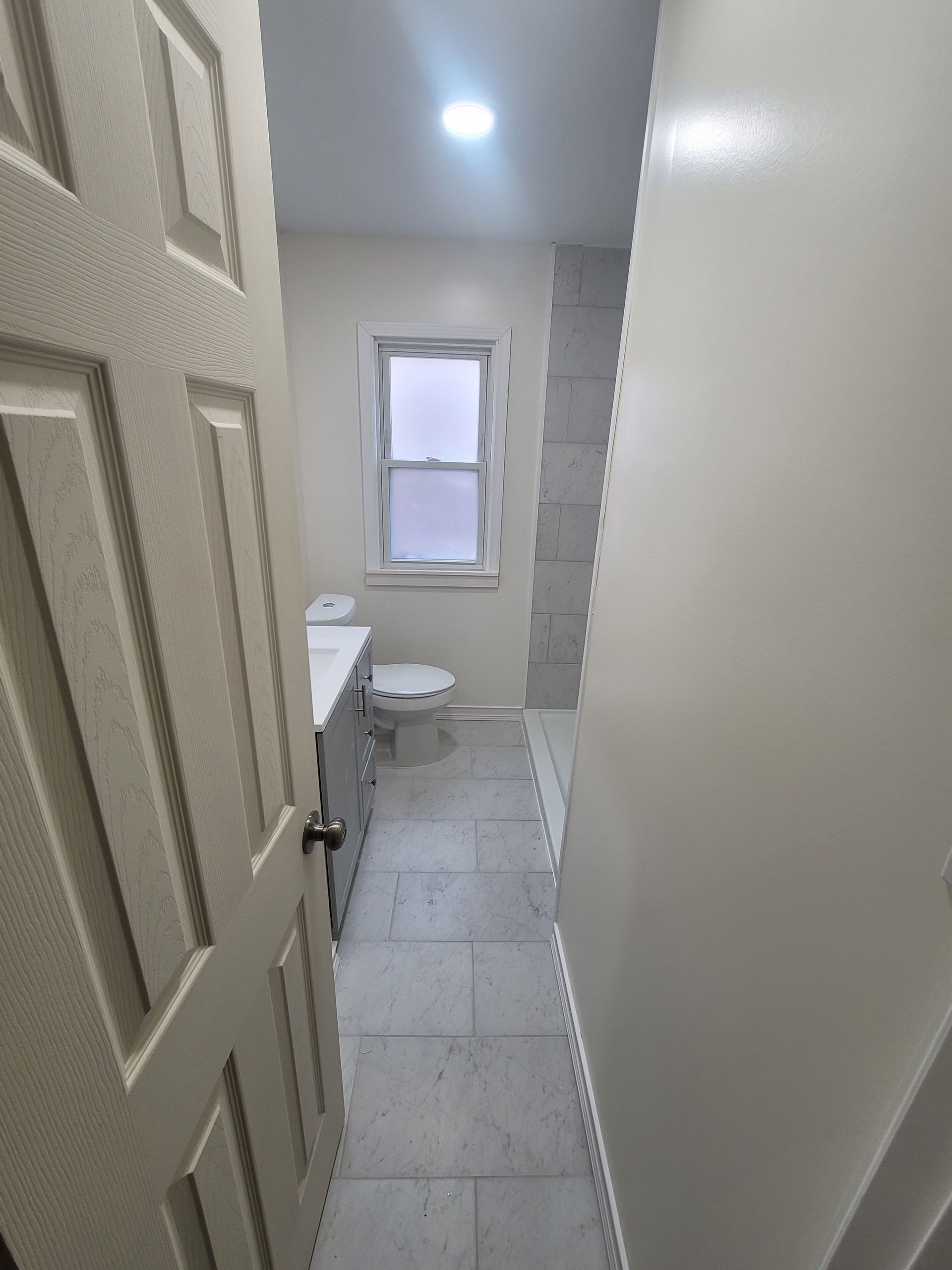 Narrow bathroom with white walls