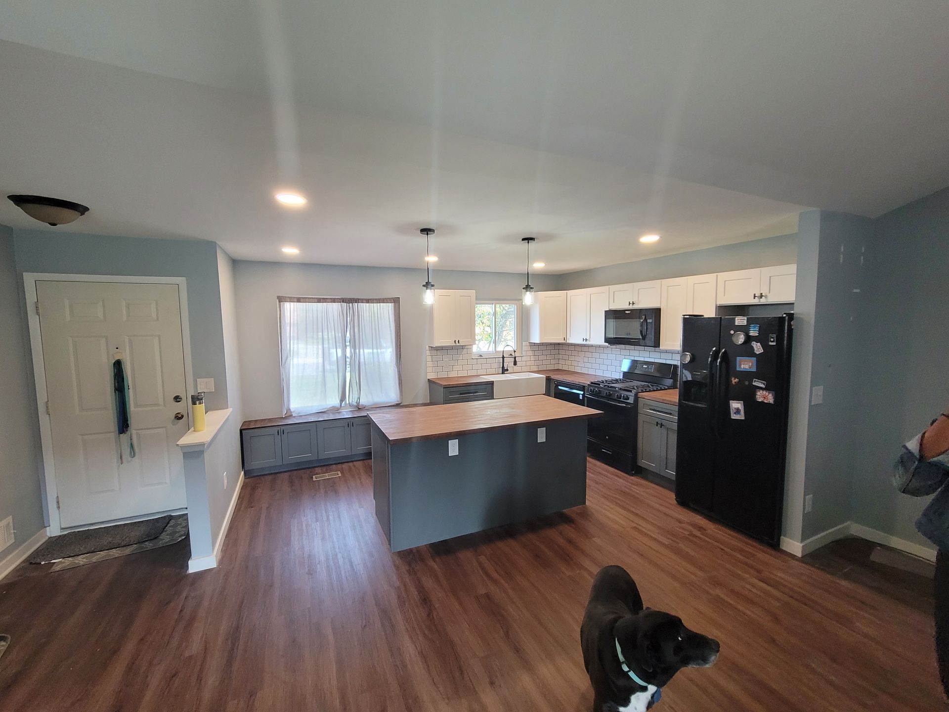 A dog is standing in a kitchen next to a refrigerator.