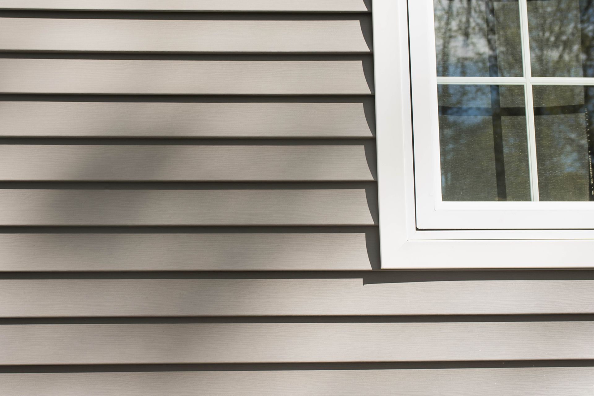 Light gray insulated siding and a white-framed window on the side