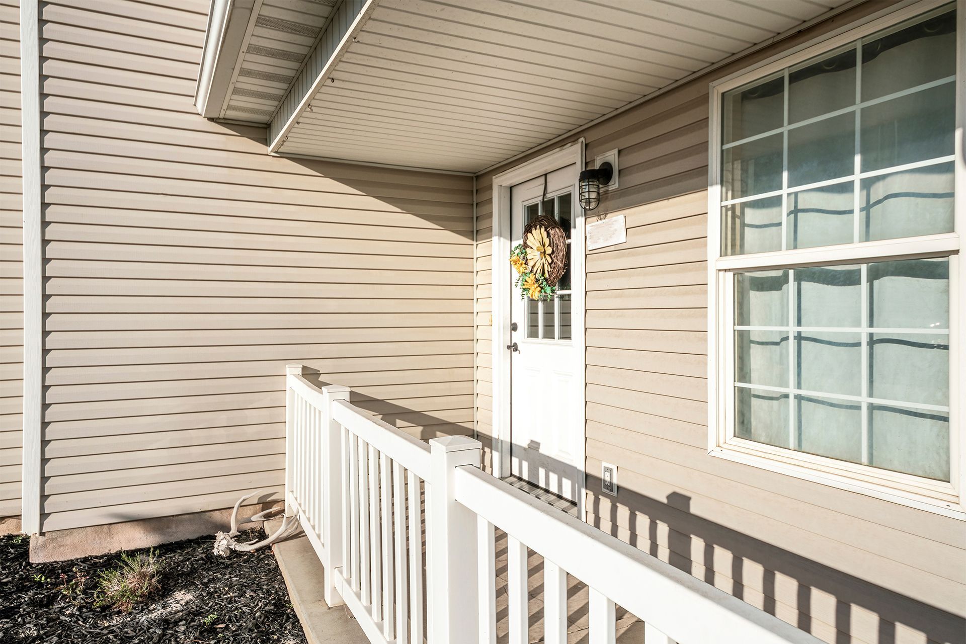 Exterior entrance with white door, window and white insulated vinyl siding
