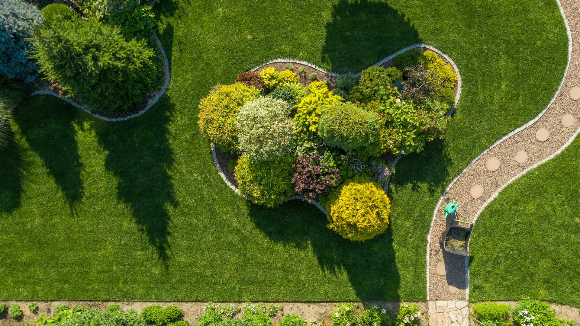 Overhead view of a lush green garden with a patterned path and flower bed.