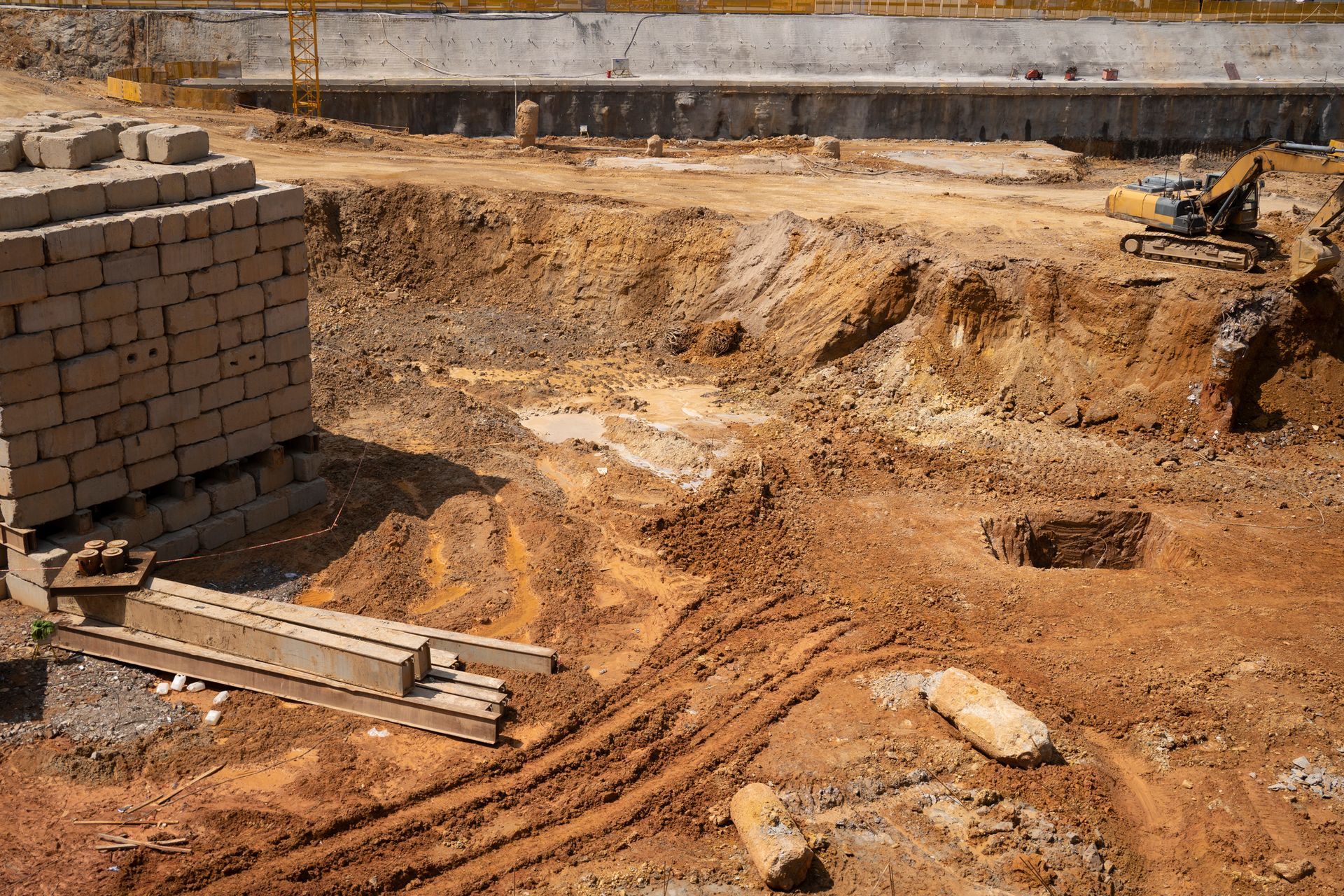 Construction site with excavated earth, brick structure, and machinery.