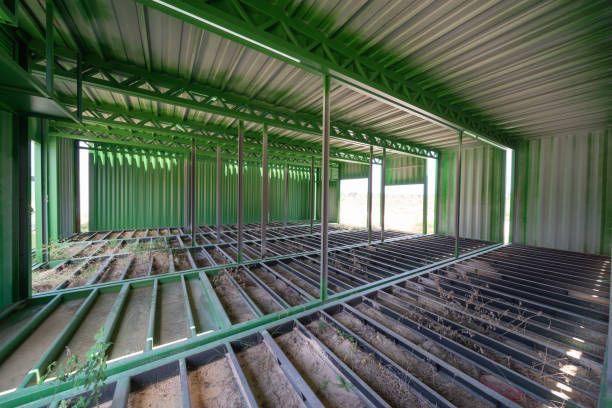 Interior view of a green metal structure, floor framework visible, natural light entering from openings.