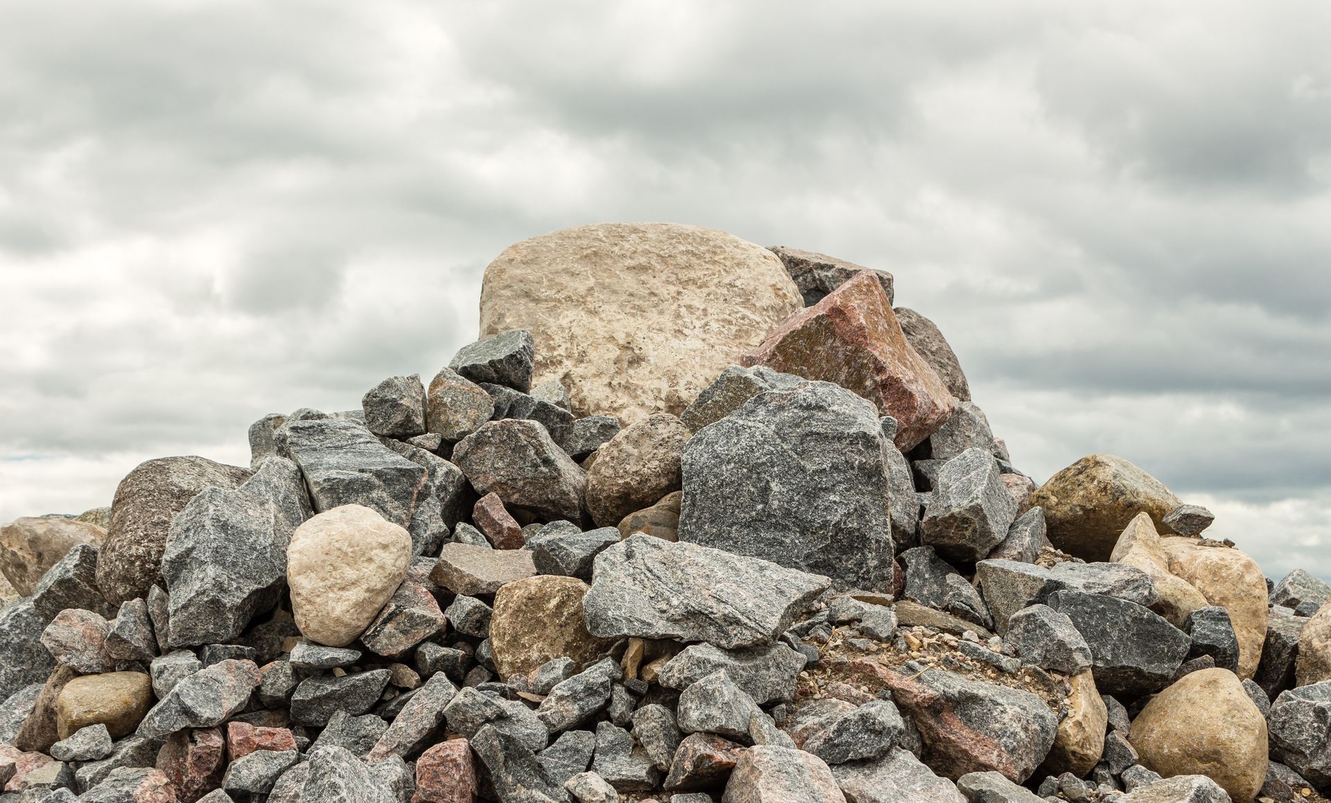 Pile of assorted rocks and stones against a cloudy sky.