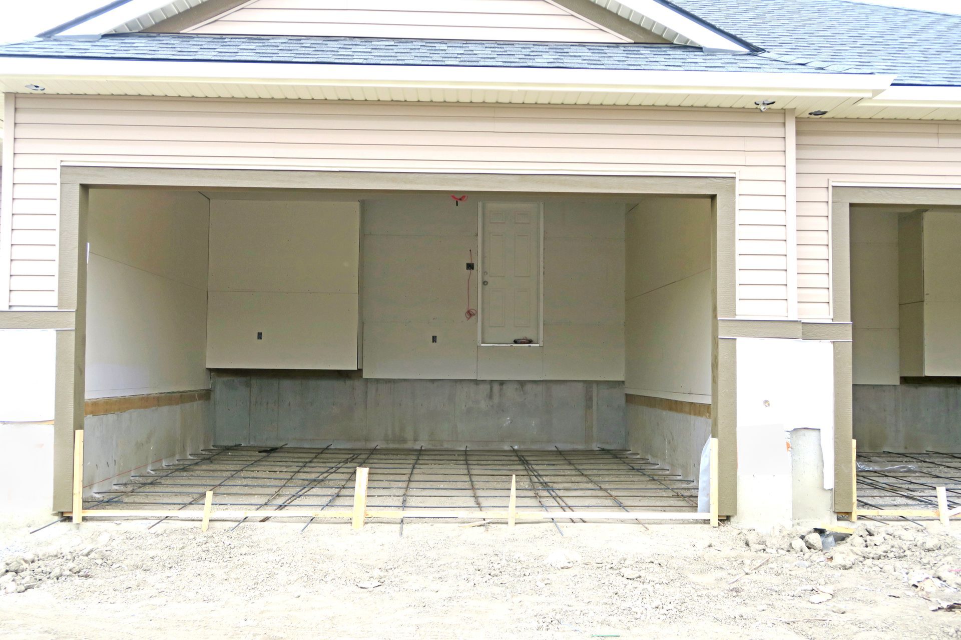 Garage under construction with concrete foundation, framing and open door.