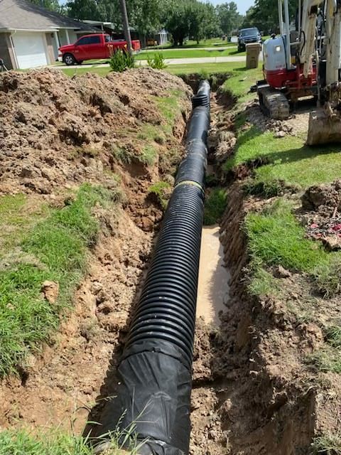 Construction site with open trench, concrete drainage tunnel, and standing water.