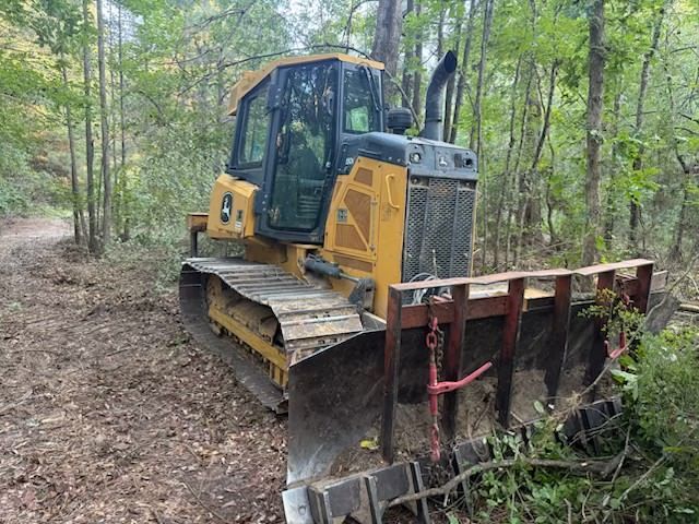 Skid steer loader with raised bucket dumping dirt onto a grassy area. Orange wheels, white and orange body.