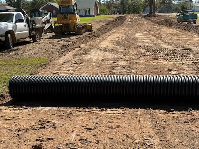 Red excavator on muddy ground with a mountain background.