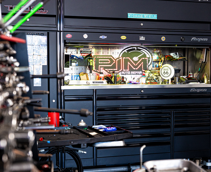 Black mechanic's tool cabinet in a cluttered garage, displaying 