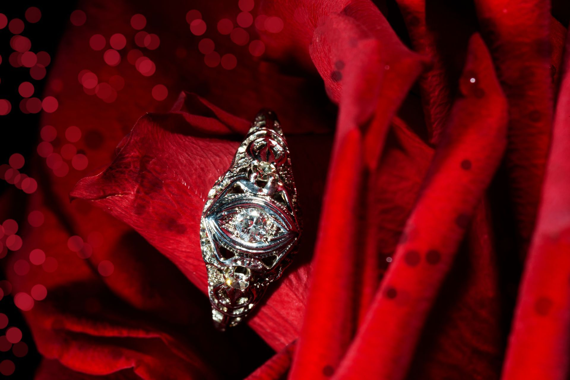 A vintage-style platinum diamond ring with a red rose