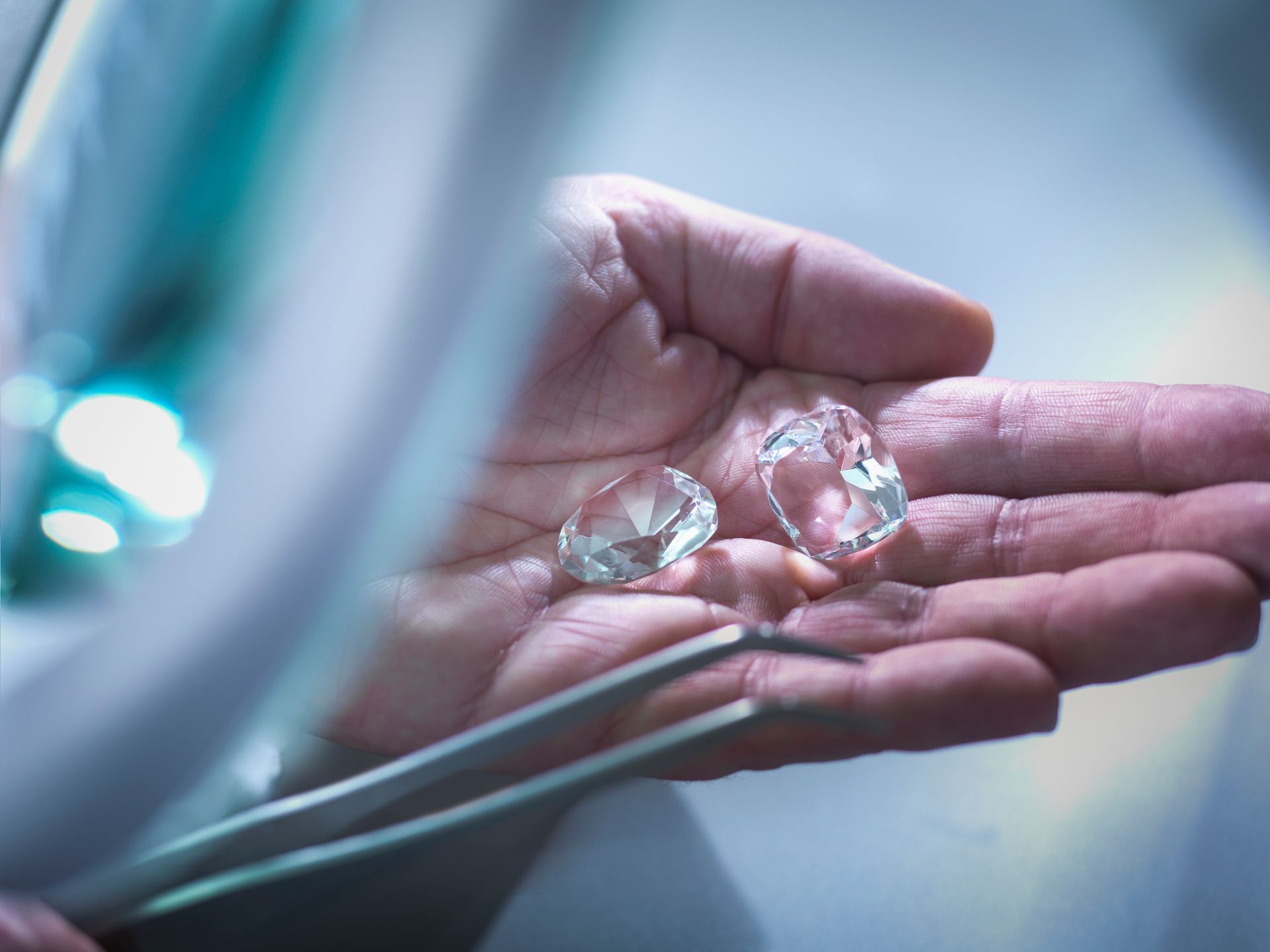 A jeweler is inspecting replica diamonds in his hand.