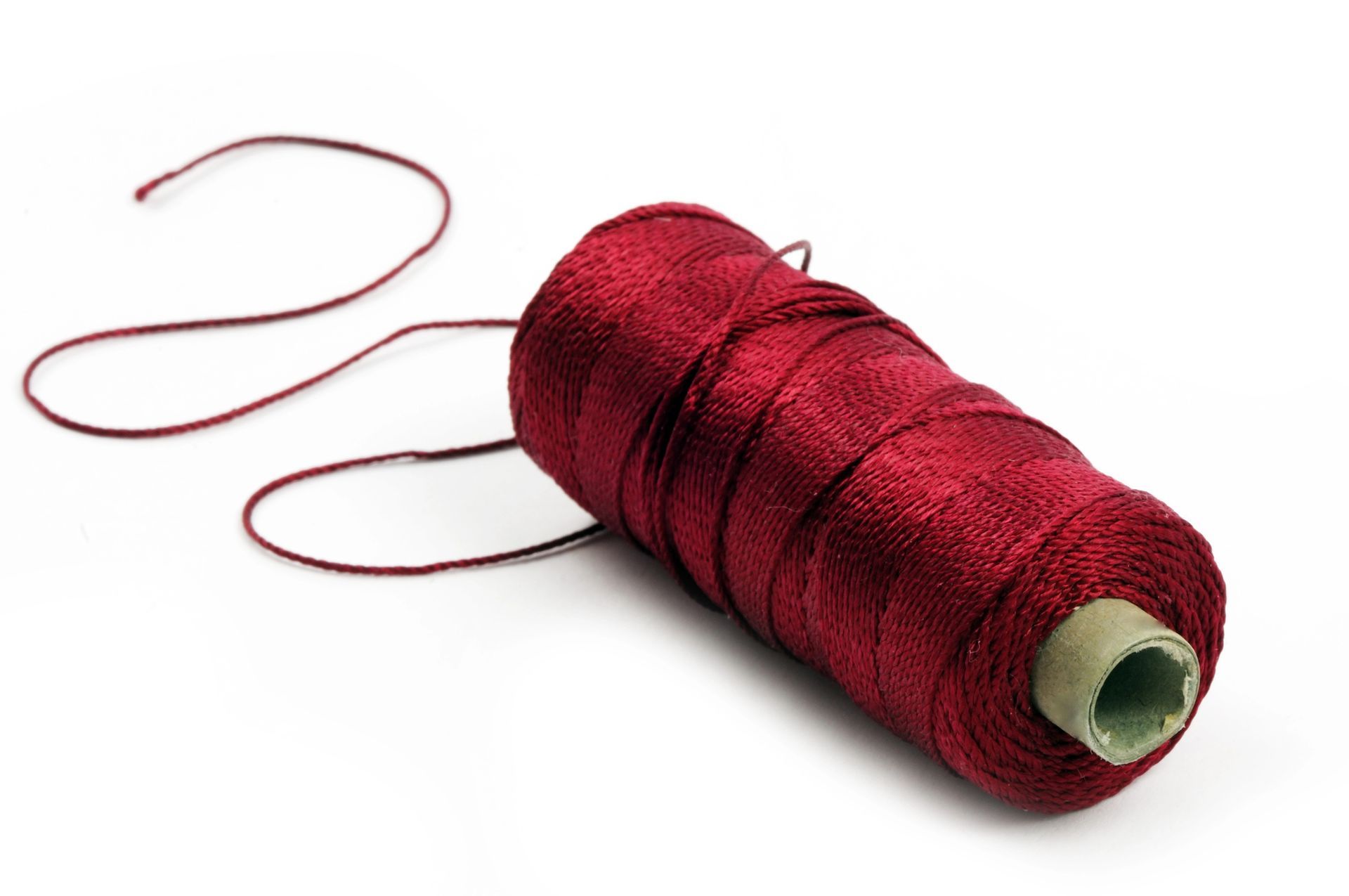 Una bobina di filo rosso scuro su sfondo bianco, con un'estremità libera che pende di lato.