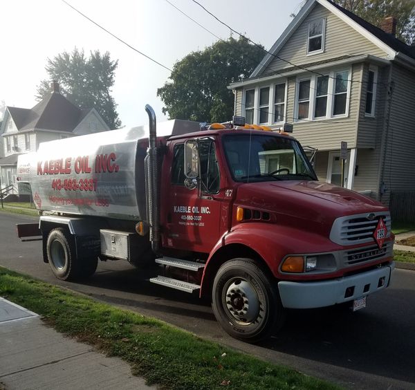 A man is walking towards a tanker truck with a hose attached to it.