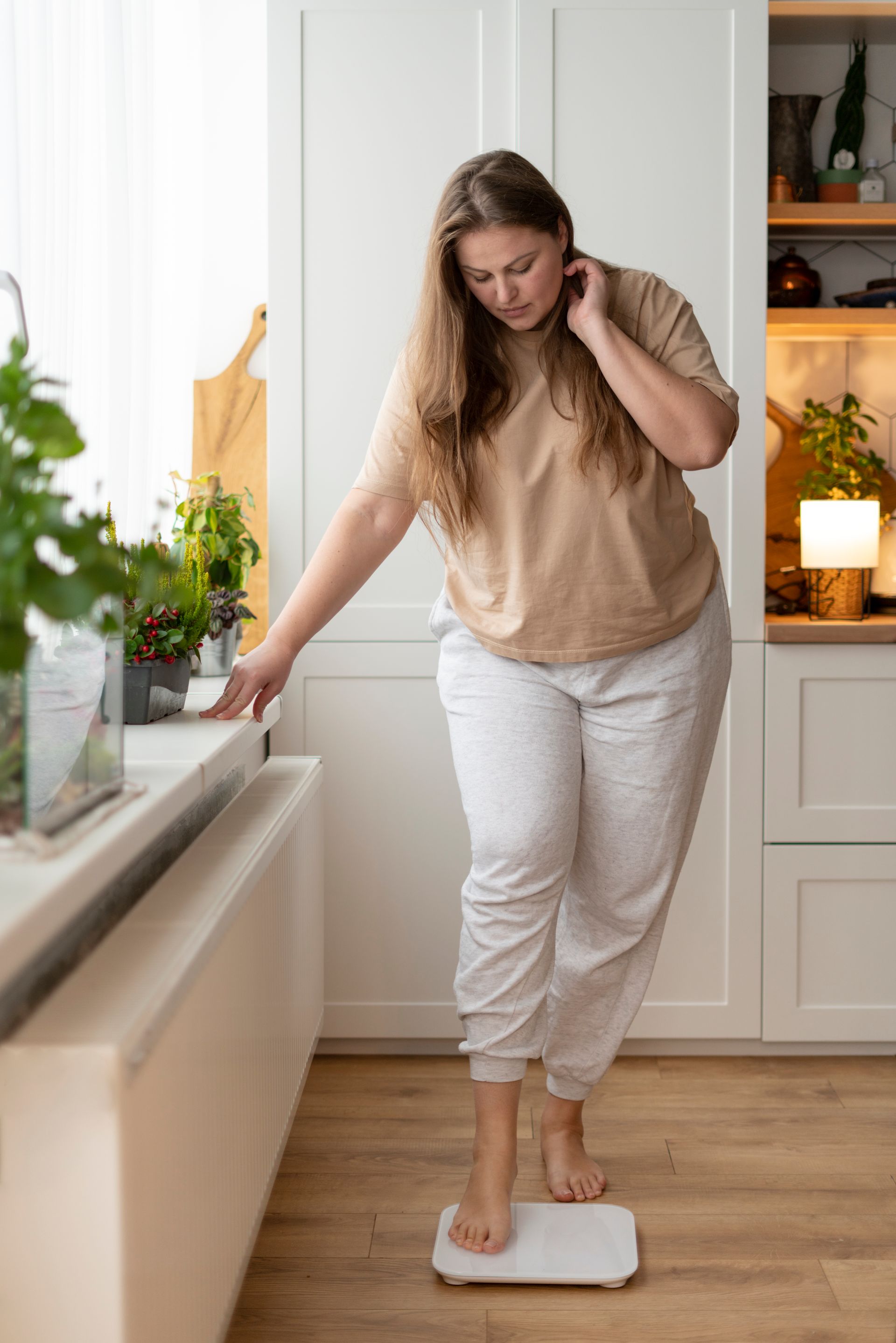 person weighing themselves on scale in kitchen