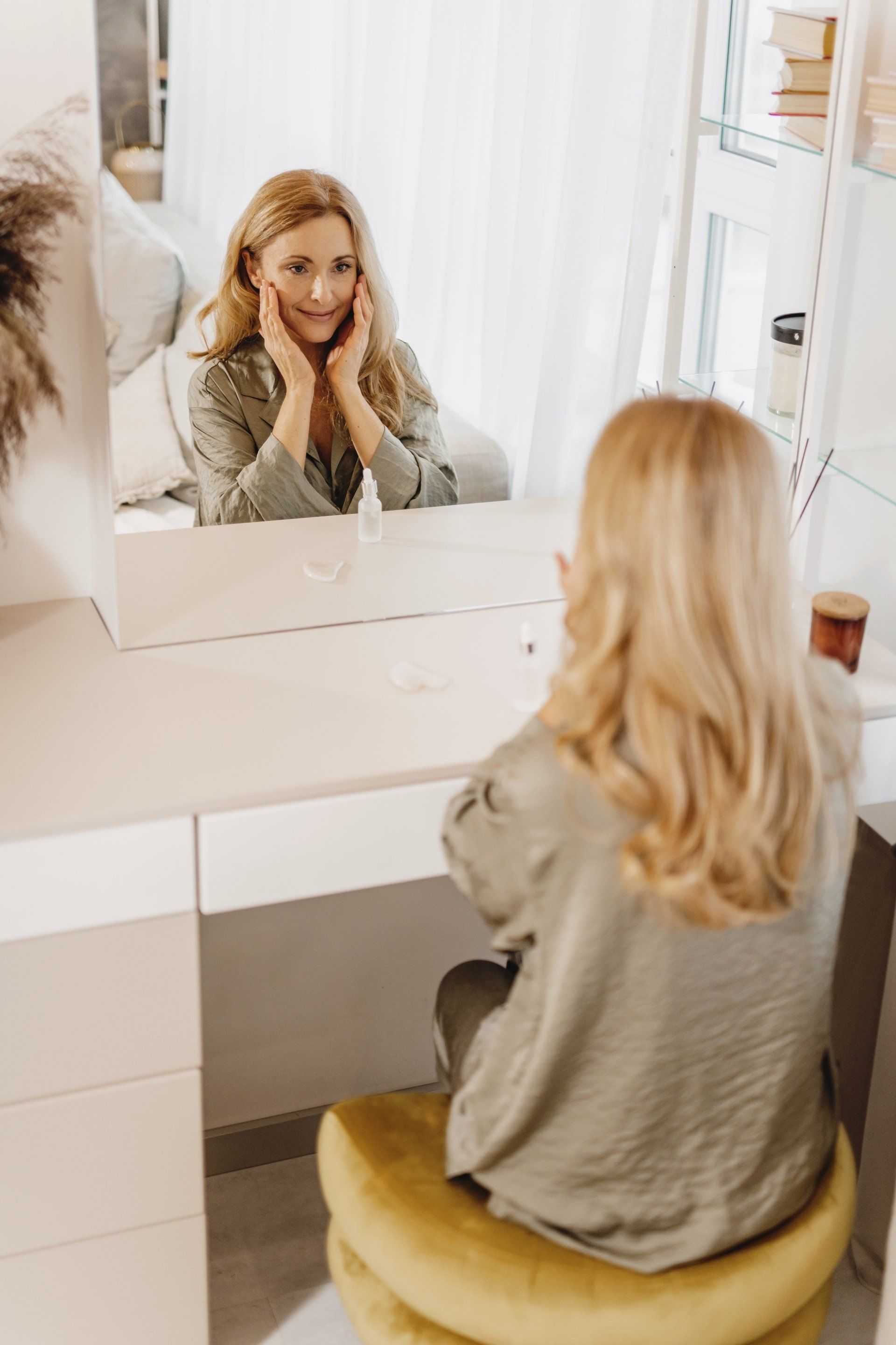 woman sitting in front of mirror touching her cheeks