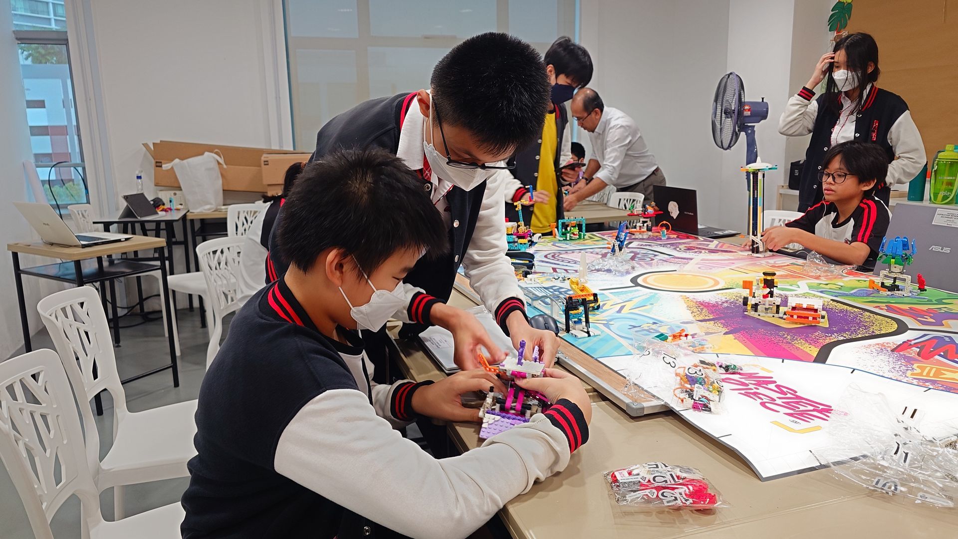 Students in uniforms building with Lego at a table in a classroom.