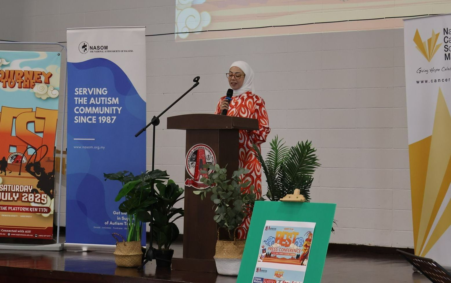 Woman speaking at a podium with banners behind her.