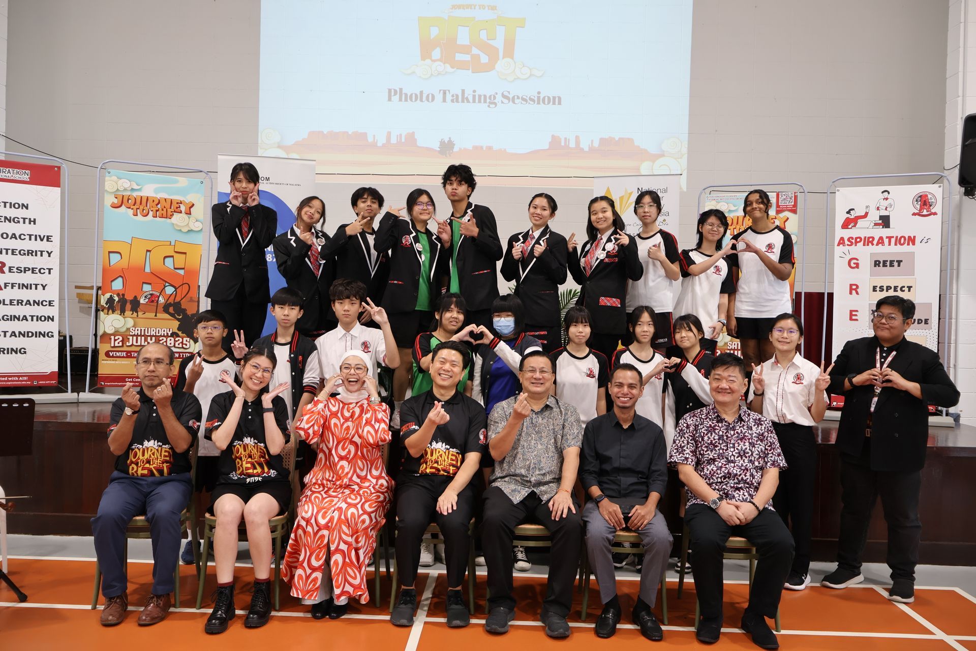 Group of people posing for a photo. Many smiling, indoors, banner in the background.