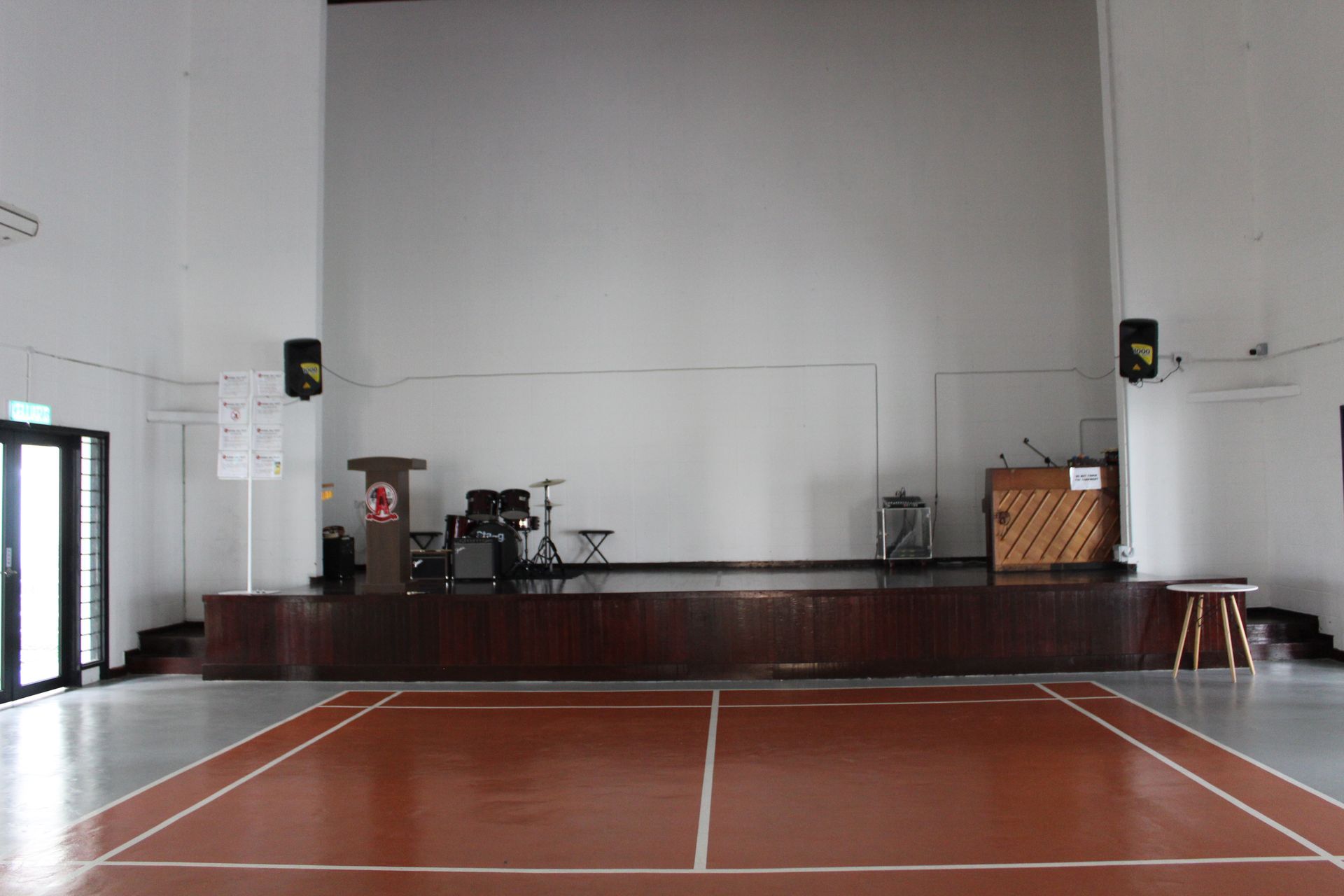 Indoor badminton court with stage and sound equipment.