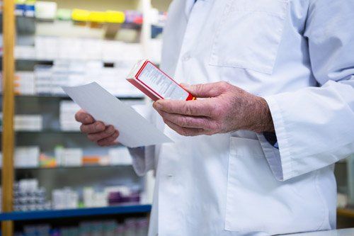 farmacista consulta una ricetta e legge le indicazioni scritte sulla confezione di un farmaco