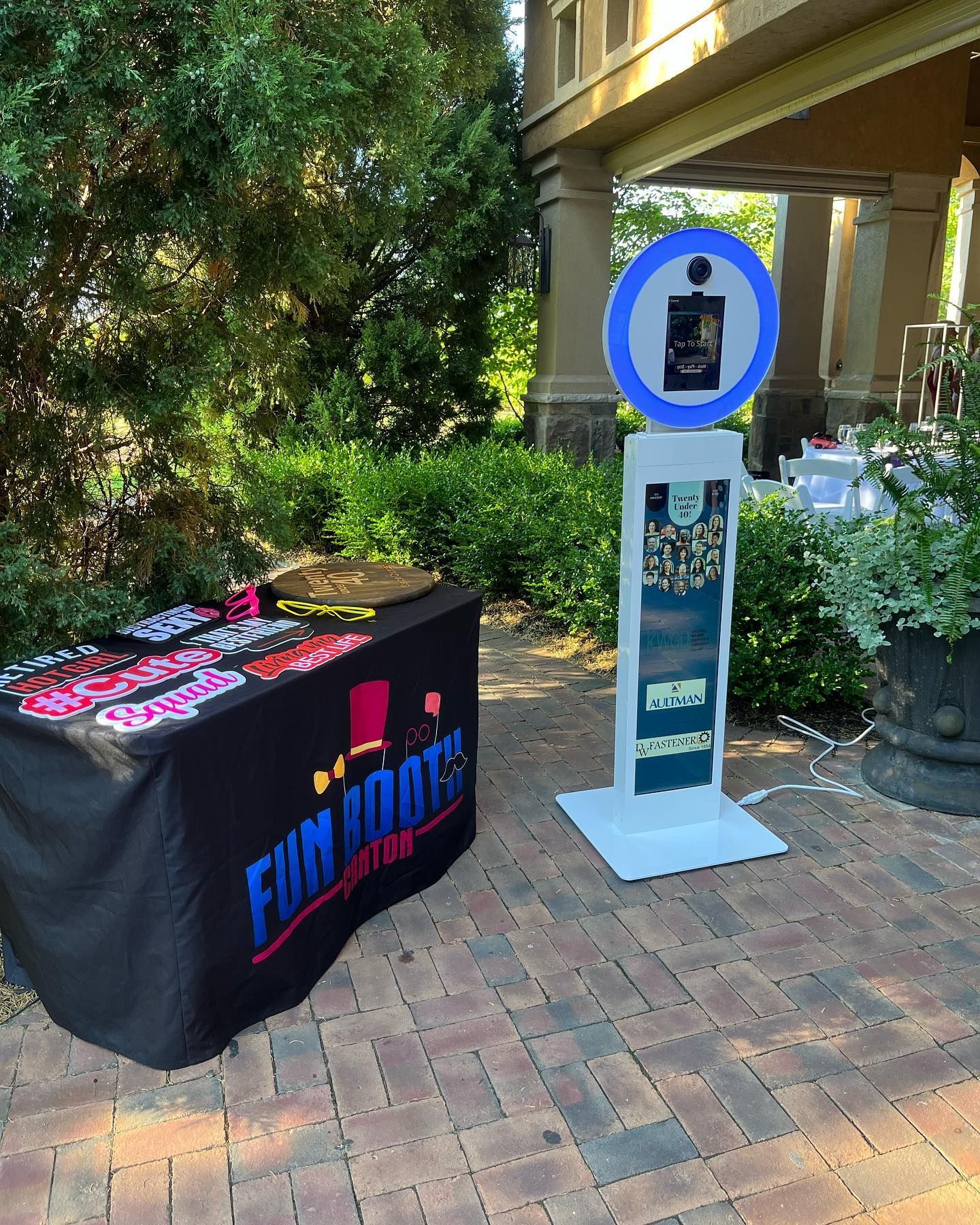 Photo booth setup at an outdoor event with props on table and booth with a sign.