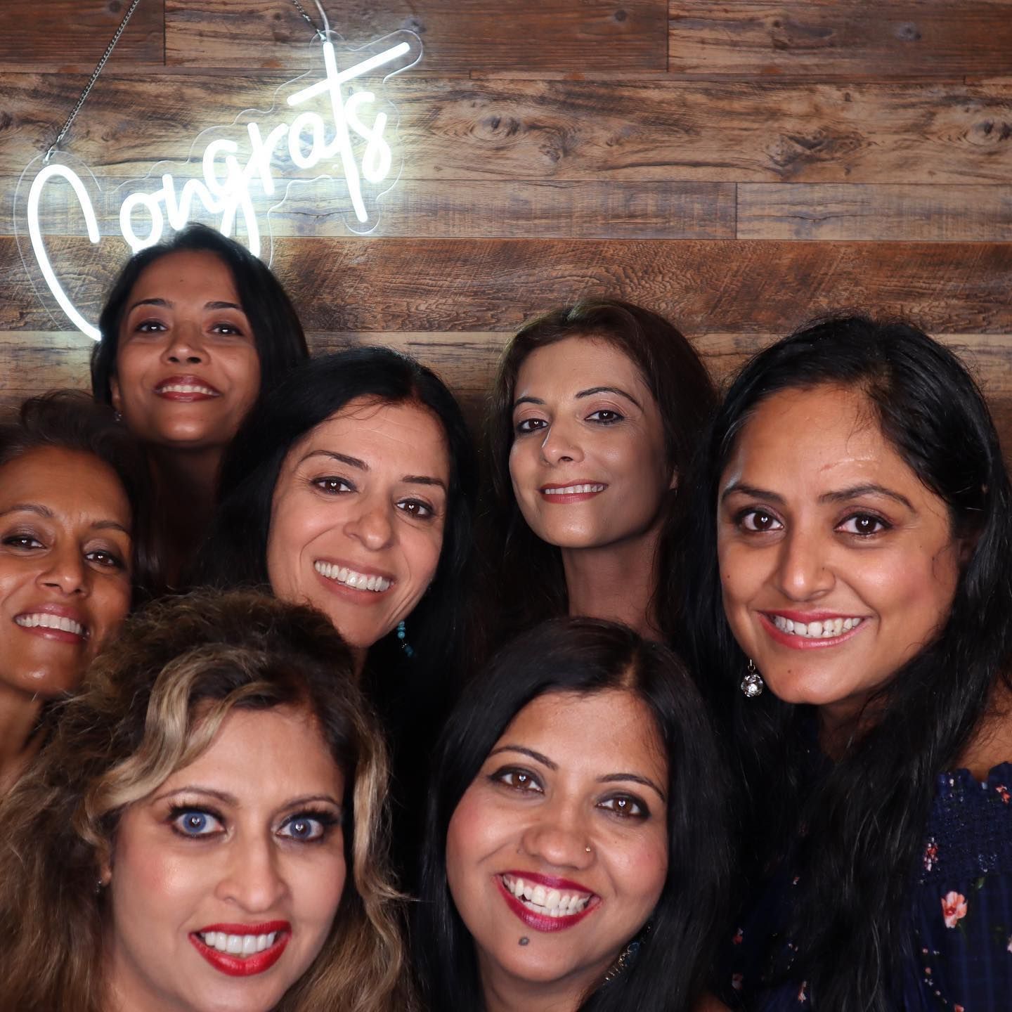 Group of women smiling, posing for a photo. Neon 
