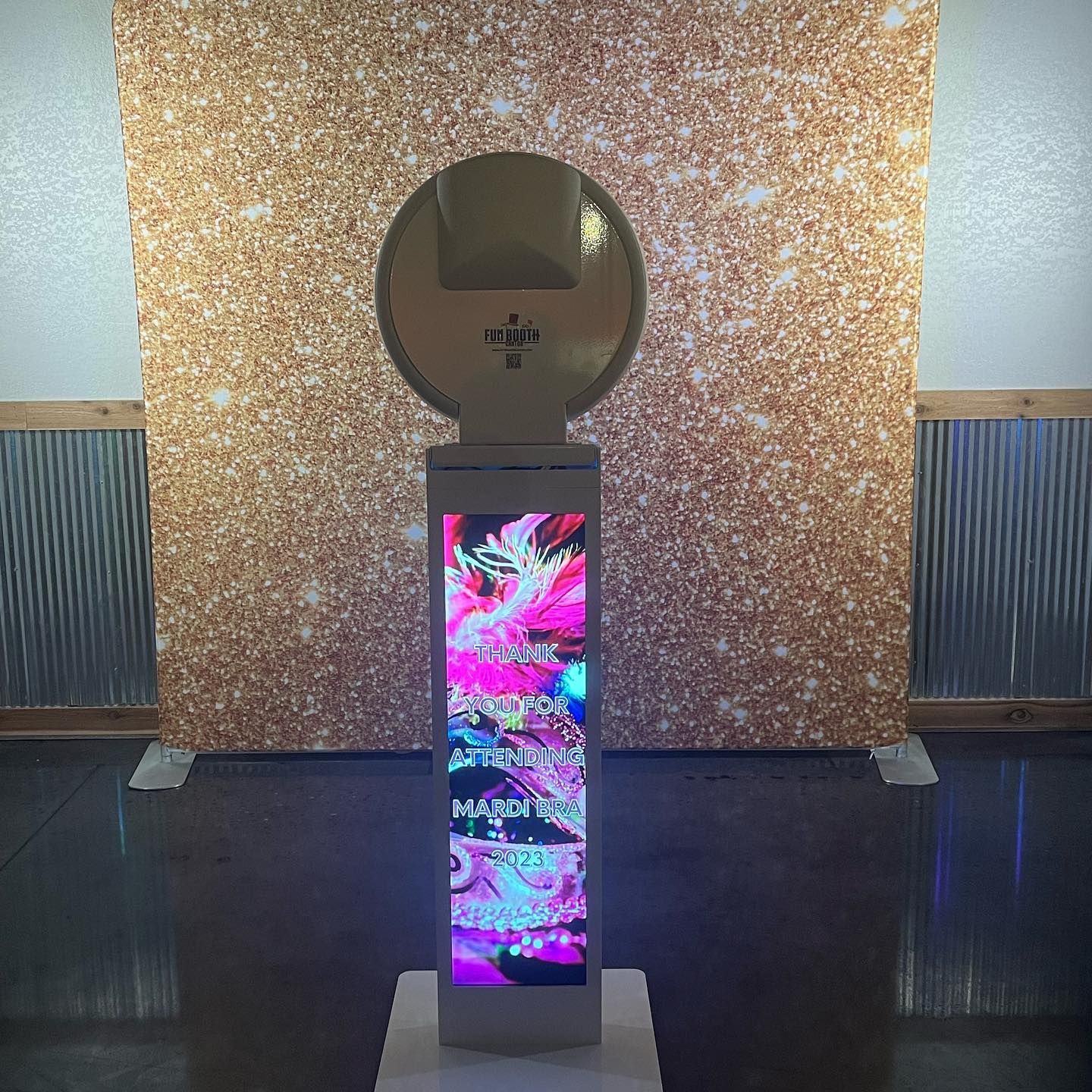 Photo booth with colorful display, in front of a gold glitter backdrop.