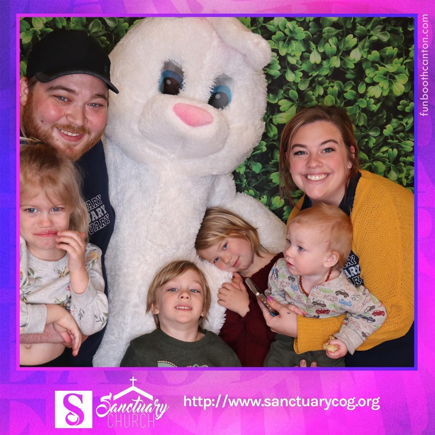 Family poses with a large Easter bunny at an event.