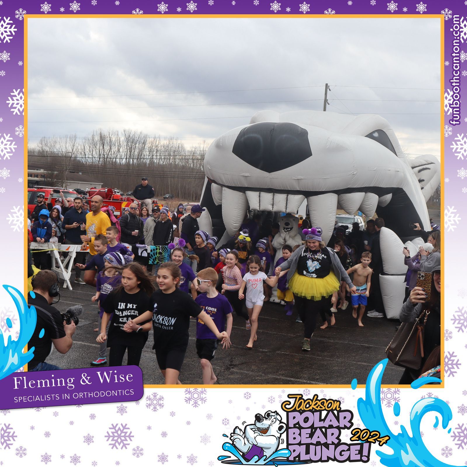 People running into a pool under a polar bear inflatable arch at a charity event.
