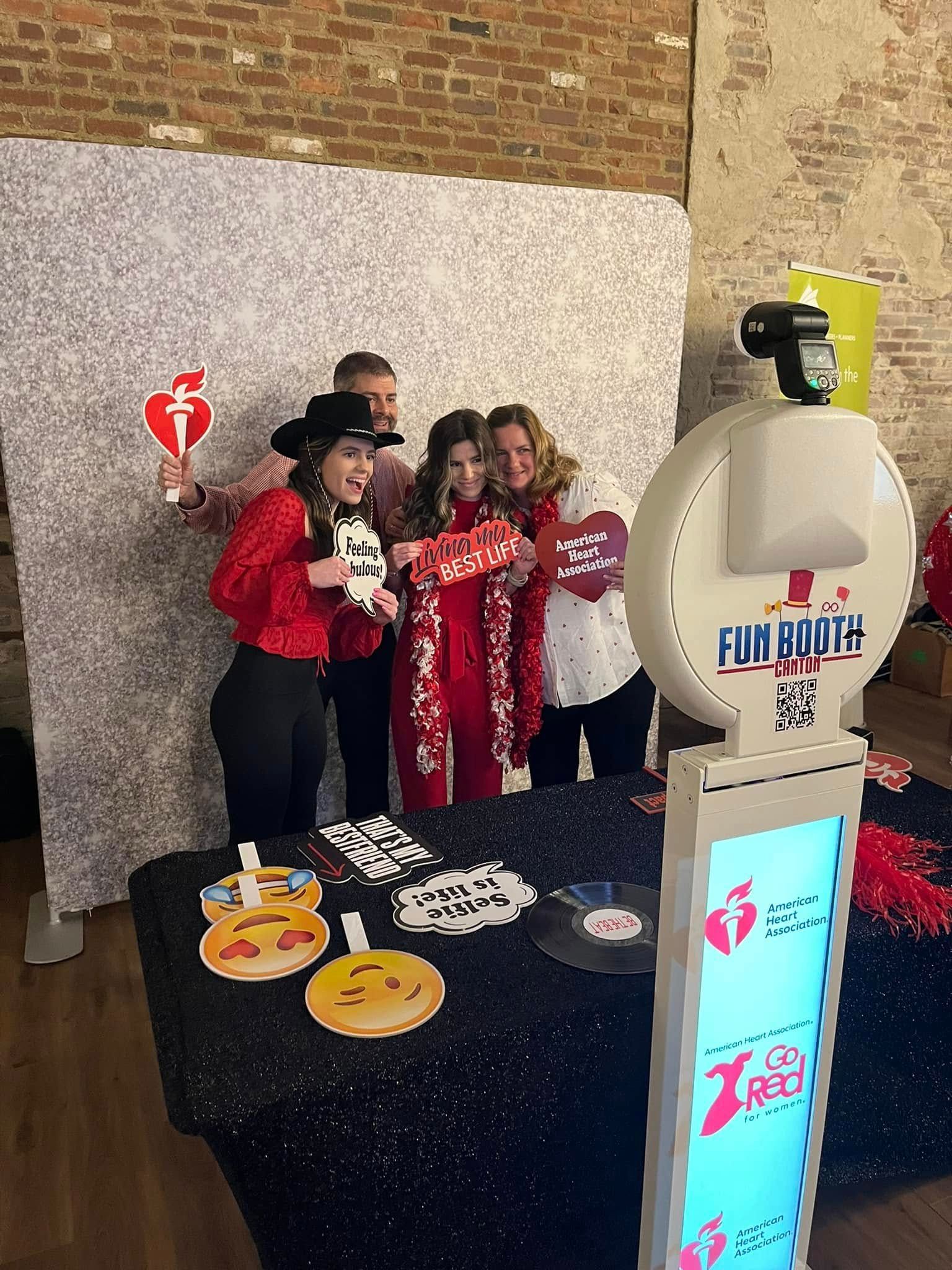 Four people pose for photo booth with props against a sparkly backdrop.