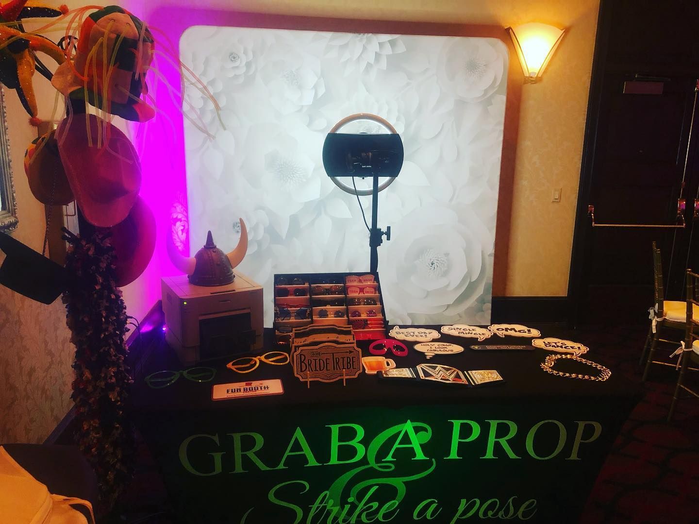 Photo booth setup with props on a table. Includes ring light, backdrop, and table cloth with 