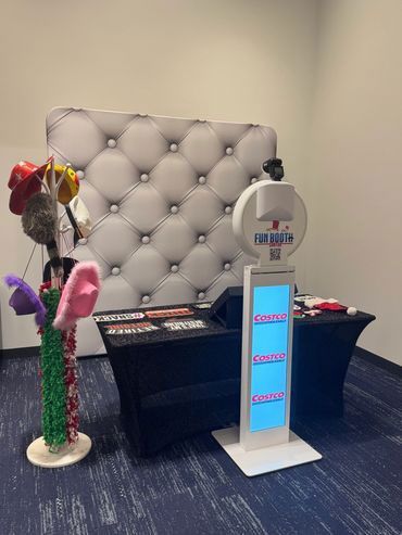 Photo booth setup with white backdrop, props, and touchscreen interface.