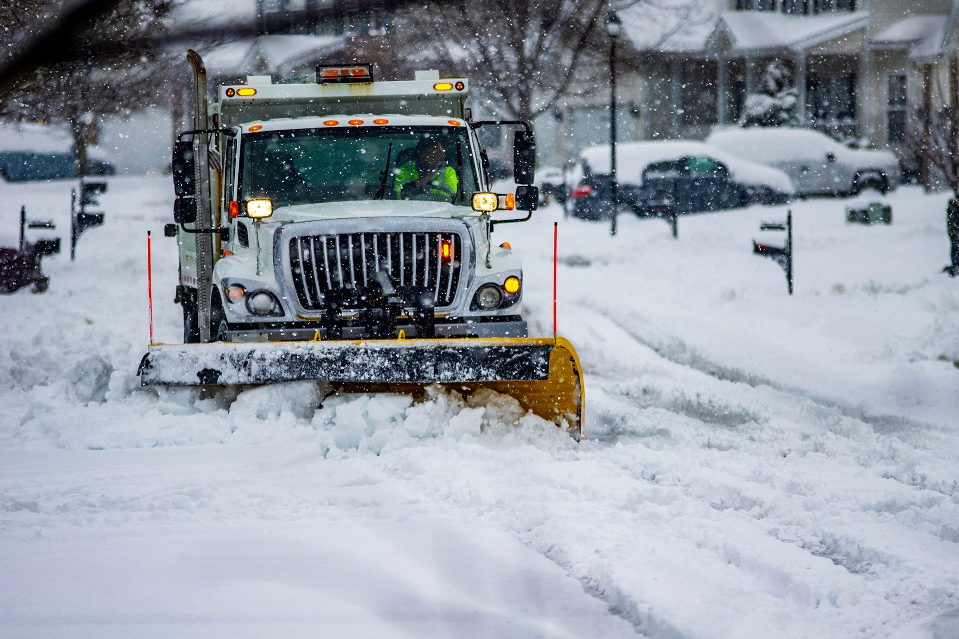 Snow Plow Is Driving Down a Snow Covered Street