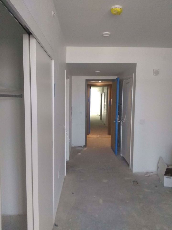 An empty hallway in a house with a blue door leading to a bedroom.