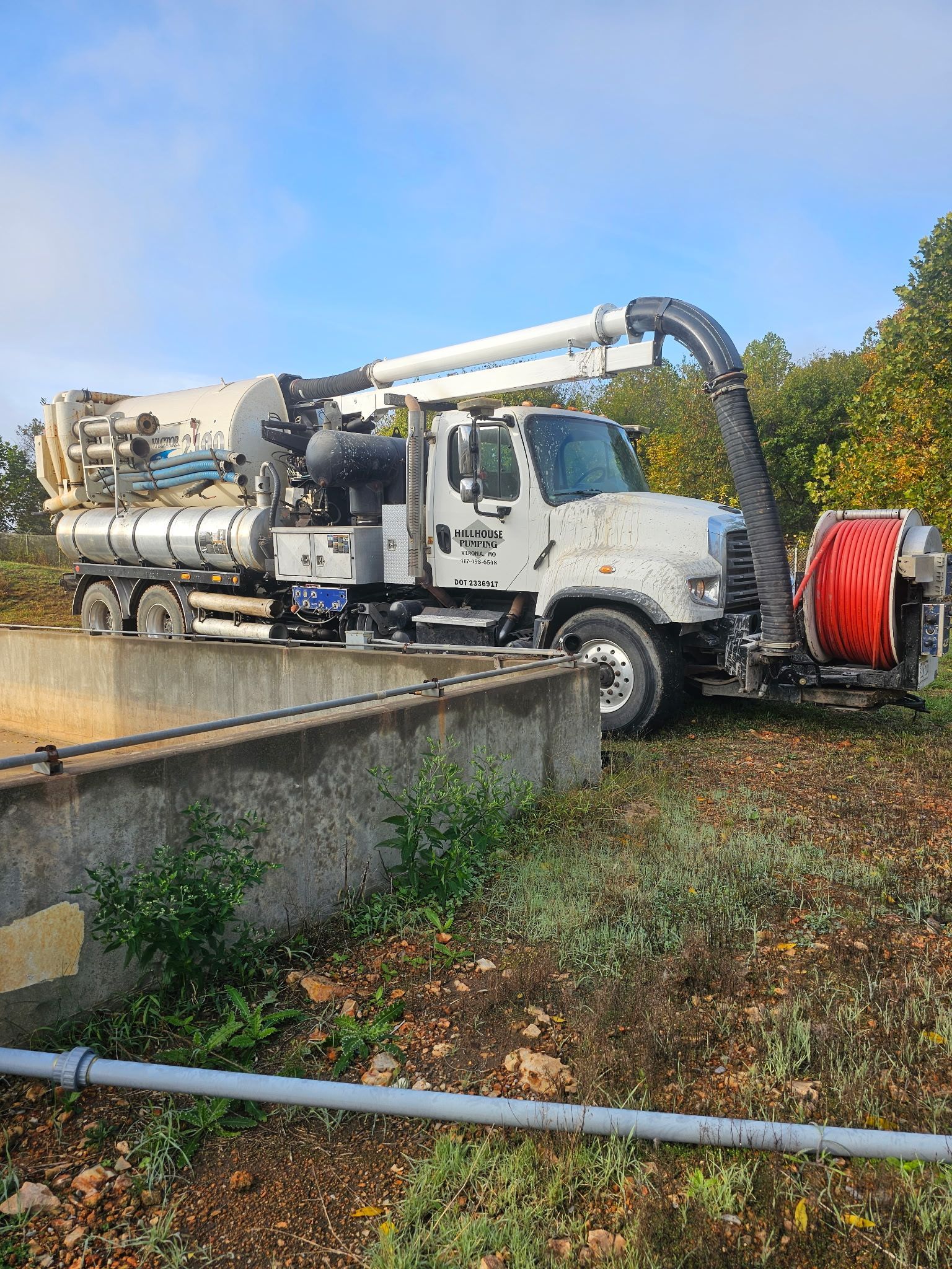 Tanker truck pumping liquid from a storage tank on a farm.