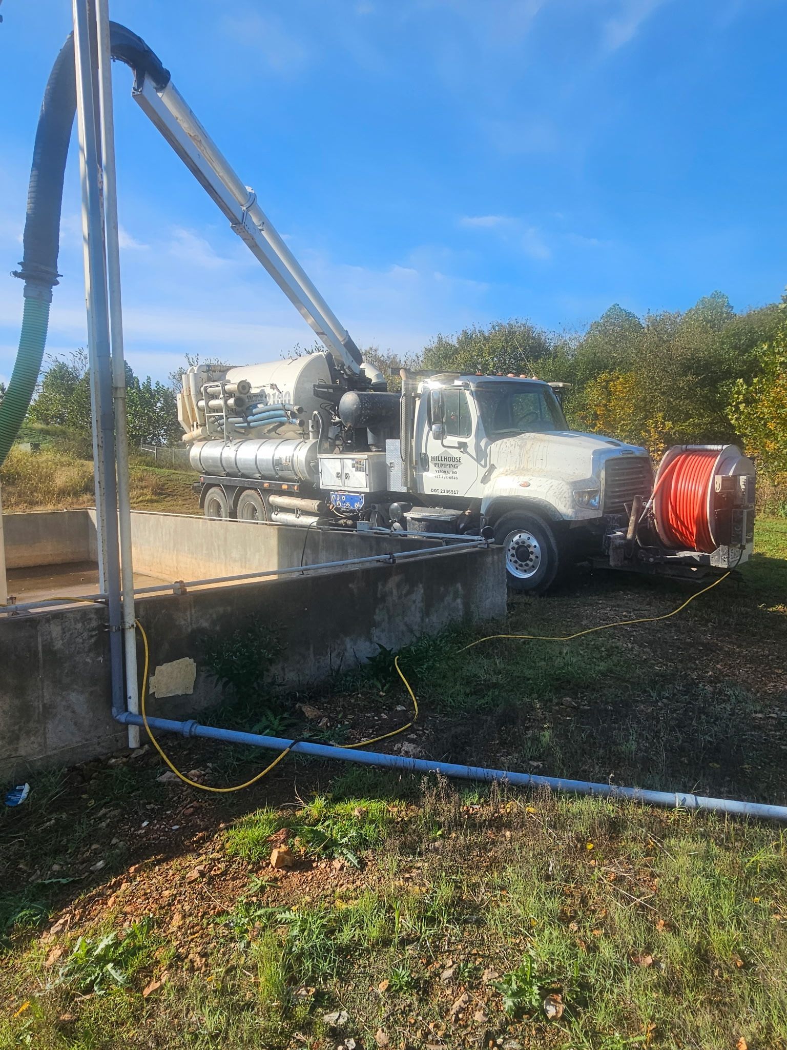 Tanker truck pumping liquid from a storage tank on a farm.