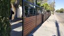 Modern wooden fence with black metal frame along a sidewalk next to a street.