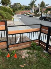 Wooden and black metal fence with a gate, in front of a street.