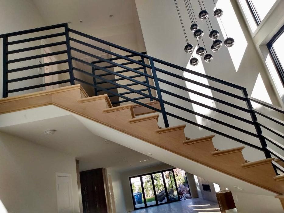 Staircase with wooden steps and black metal railing in a bright, modern home.