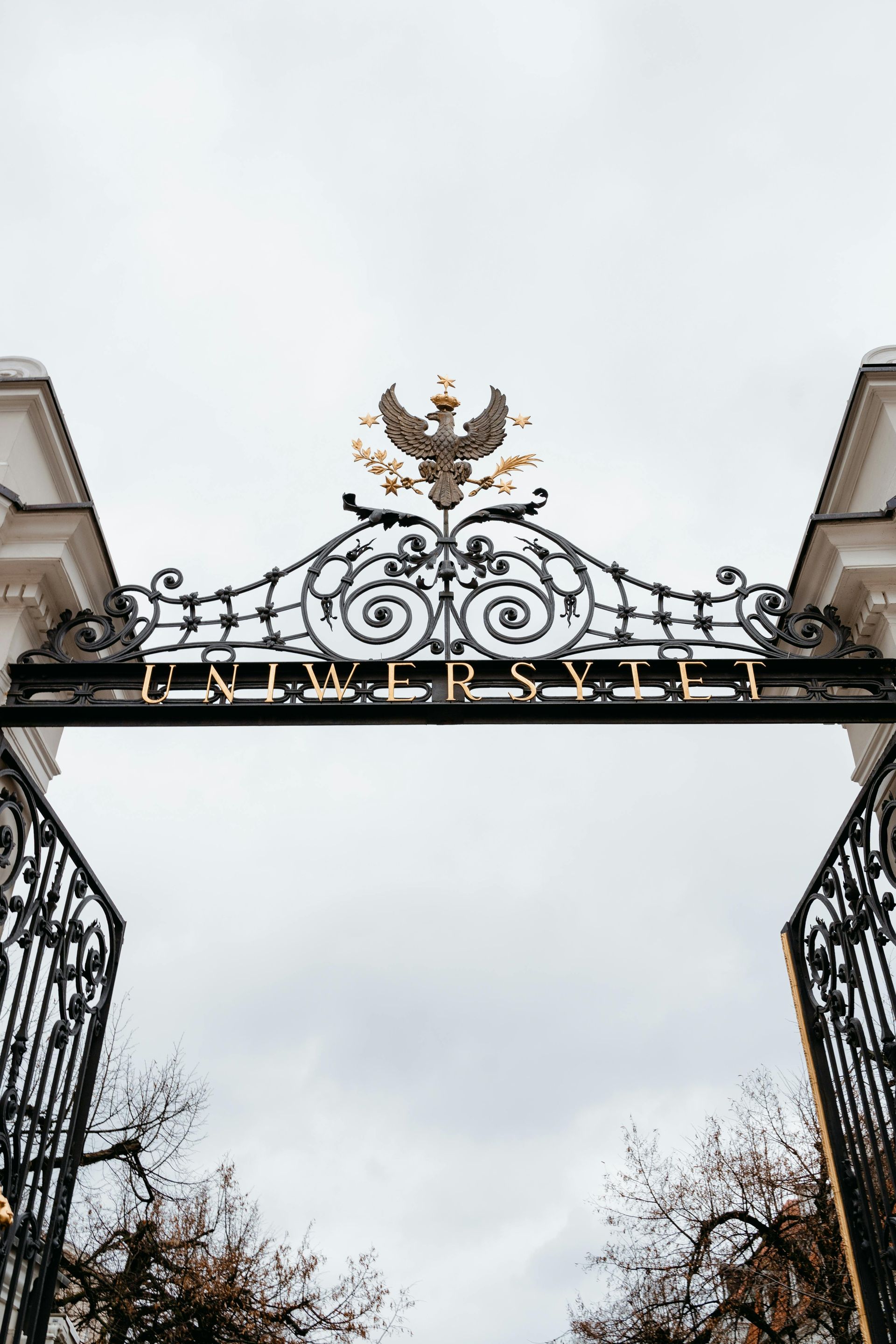 Ornate black and gold gate, topped with an eagle, reads 