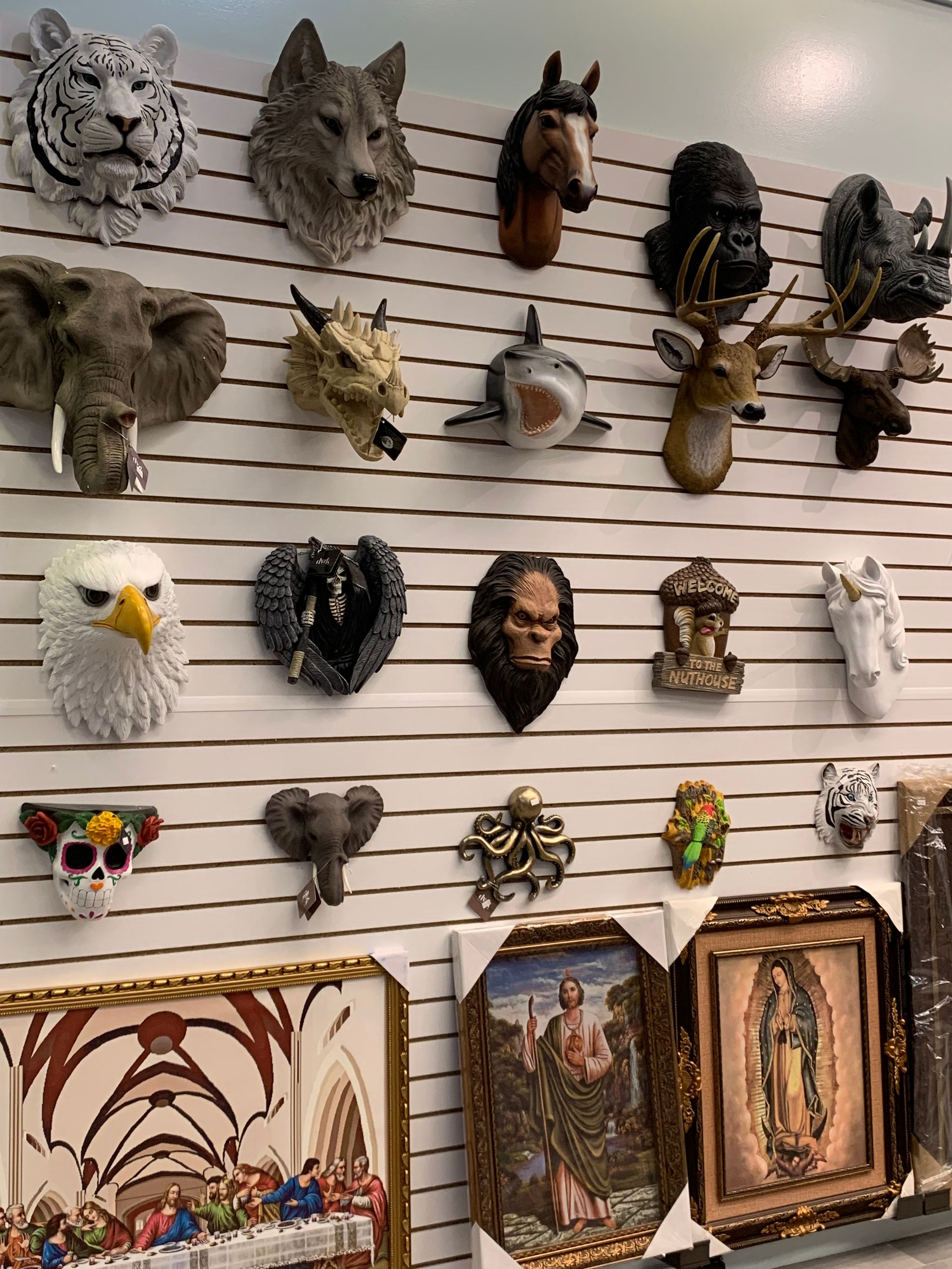 A wall filled with a variety of animal heads and paintings.